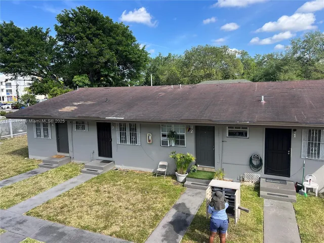 a view of a house with table and chairs under an umbrella