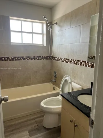 a bathroom with a granite countertop sink a toilet and bathtub