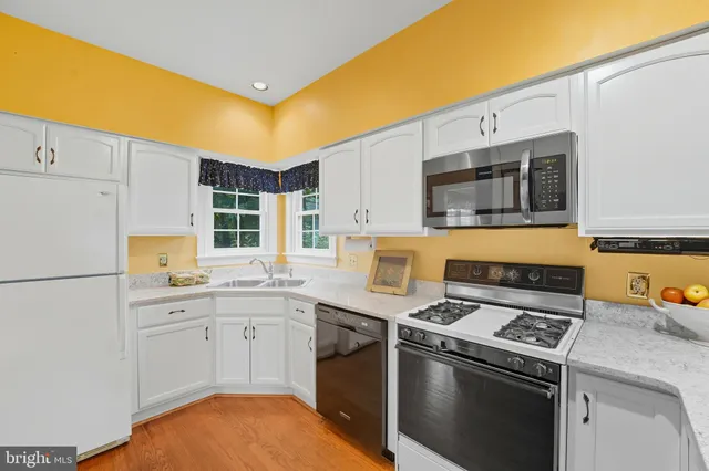 an empty room with a kitchen space and wooden floor