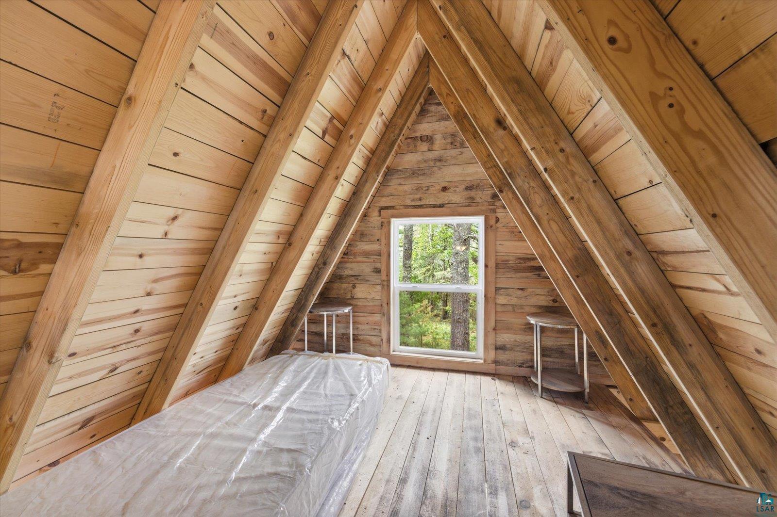 5298 Long Island Tower, MN 55790 - Photo 21 of 31 Vaulted wood-paneled ceiling with exposed beams, wood-finish flooring, and a window with exterior tree scenery