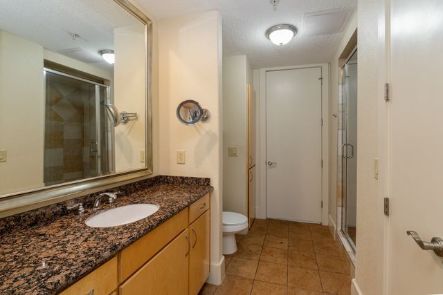 a bathroom with a granite countertop sink a toilet a mirror and shower