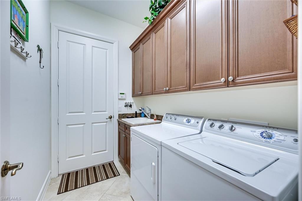 7587 Moorgate Point Way Naples, FL 34113 - Photo 44 of 50 Built-in cabinetry, utility sink, white paneled door, and tiled flooring