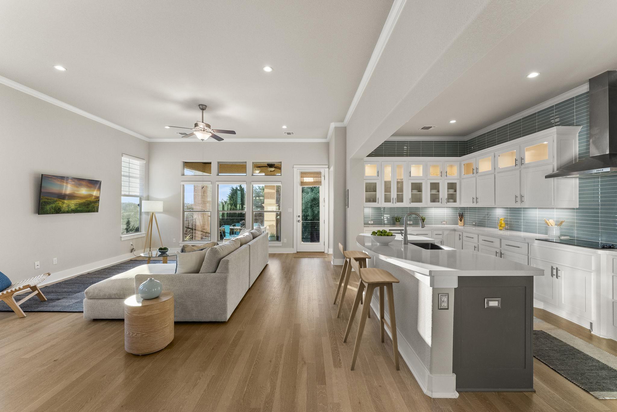 5502 Patagonia Pass Austin, TX 78738 - Photo 1 of 34 Kitchen featuring white cabinetry, glass insert cabinets, a breakfast bar, wall chimney range hood, and crown molding