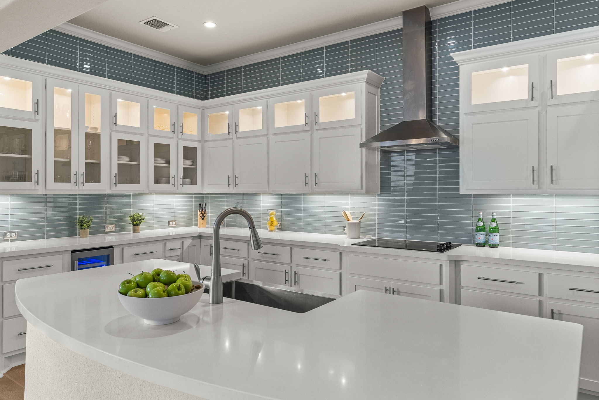 5502 Patagonia Pass Austin, TX 78738 - Photo 10 of 34 Kitchen featuring wall chimney range hood, white cabinetry, glass insert cabinets, crown molding, and light stone counters