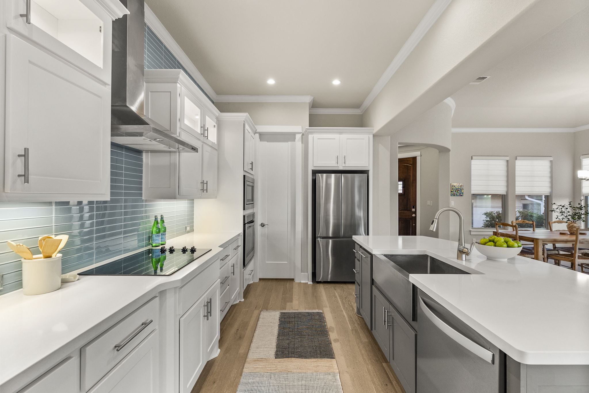 5502 Patagonia Pass Austin, TX 78738 - Photo 12 of 34 Kitchen featuring white cabinetry, wall chimney range hood, stainless steel appliances, light wood-style flooring, and crown molding