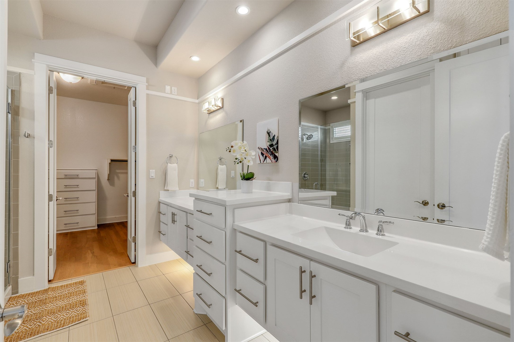 5502 Patagonia Pass Austin, TX 78738 - Photo 16 of 34 Bathroom featuring a shower stall, two vanities, a walk in closet, light tile patterned floors, and recessed lighting