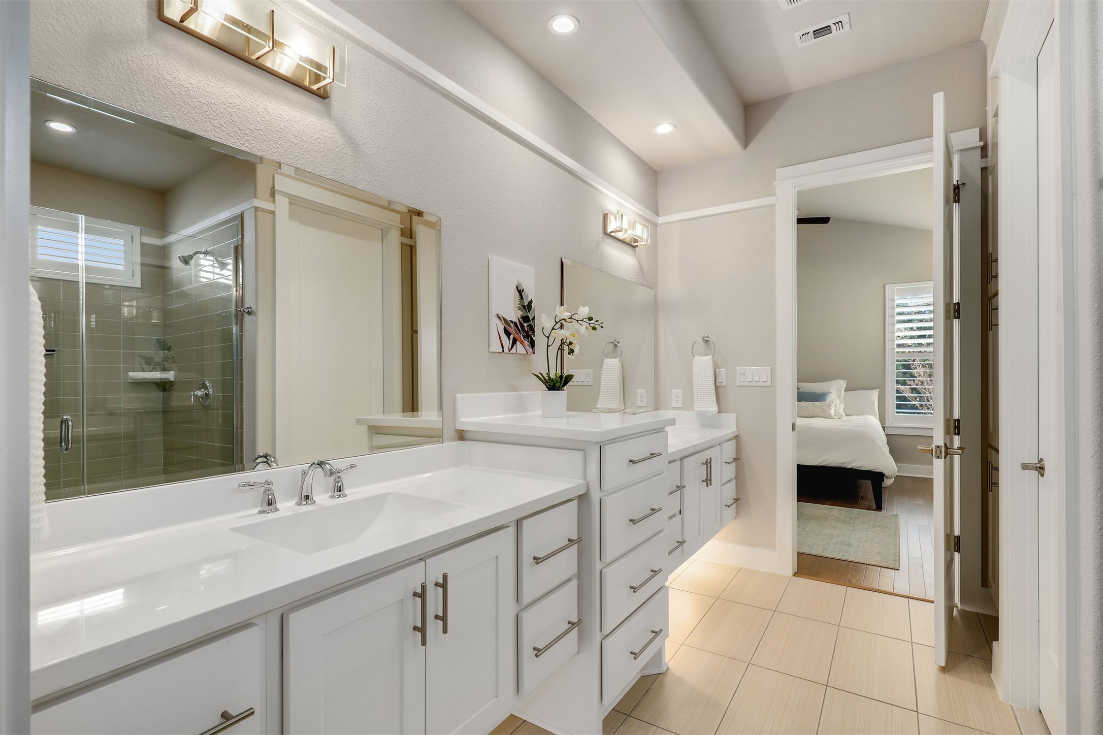 5502 Patagonia Pass Austin, TX 78738 - Photo 17 of 34 Ensuite bathroom with two vanities, plenty of natural light, a stall shower, recessed lighting, and light tile patterned floors