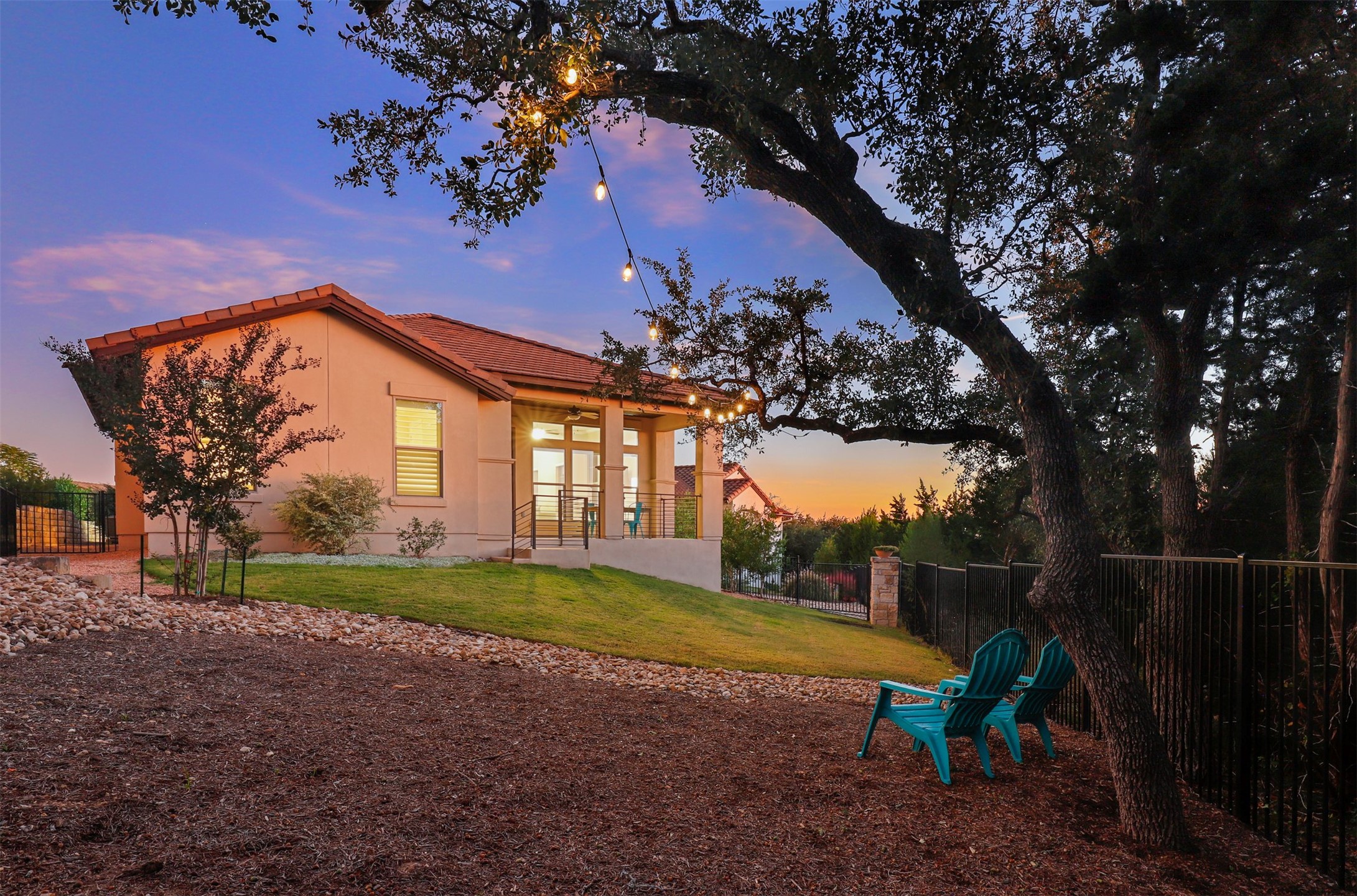 5502 Patagonia Pass Austin, TX 78738 - Photo 19 of 34 Back of property at dusk featuring stucco siding, a tile roof, and a patio area