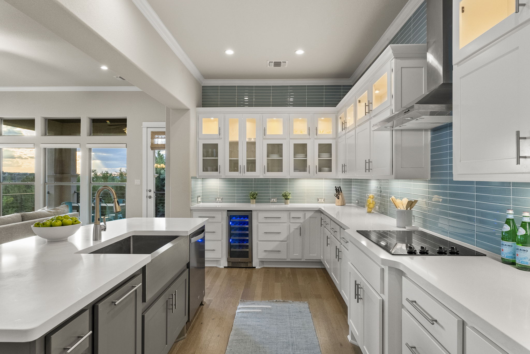 5502 Patagonia Pass Austin, TX 78738 - Photo 2 of 34 Kitchen featuring white cabinets, wall chimney range hood, an island with sink, glass insert cabinets, and crown molding