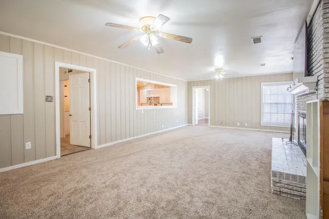 a view of a livingroom with a chandelier fan and windows