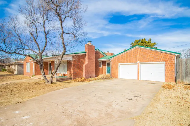 a view of yellow house with large trees