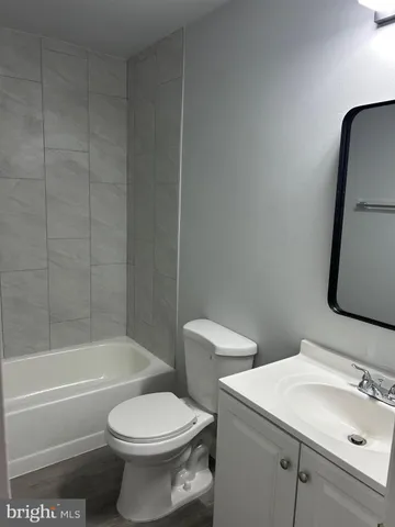 a view of an empty room with wooden floor and a ceiling fan