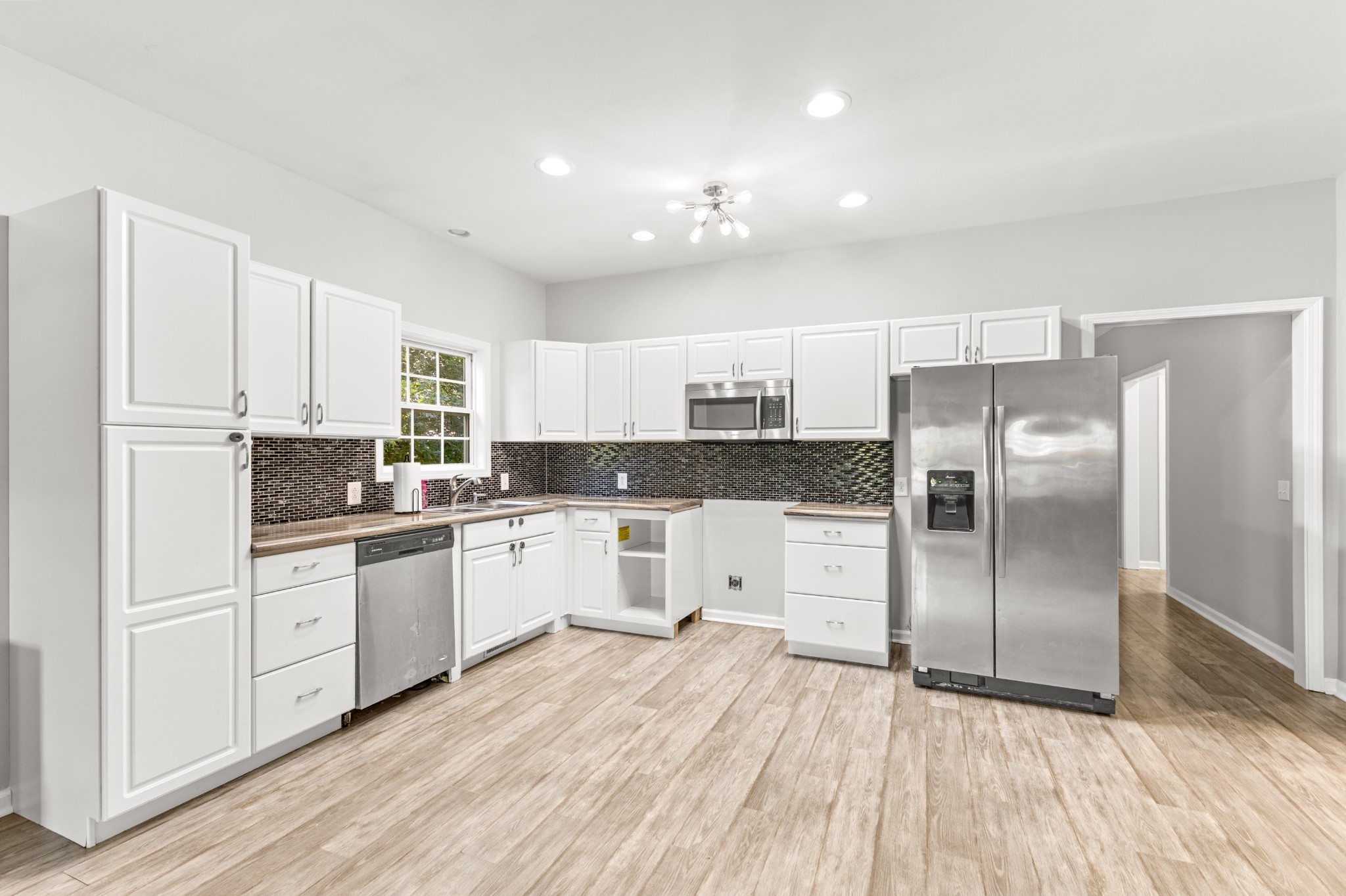 1010 Jacob's Valley Road Joelton, TN 37080 - Photo 22 of 33 a kitchen with granite countertop a refrigerator oven a sink dishwasher and white cabinets with wooden floor