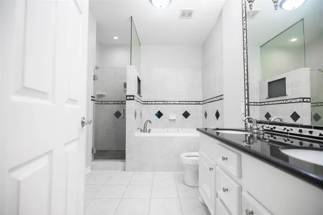 a bathroom with a granite countertop sink a toilet a mirror and shower