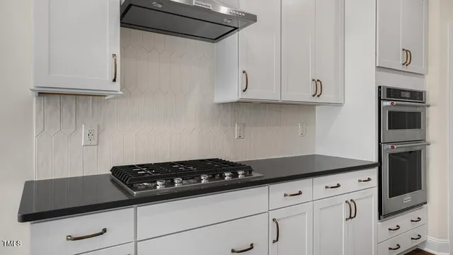 a kitchen with white cabinets and a stove