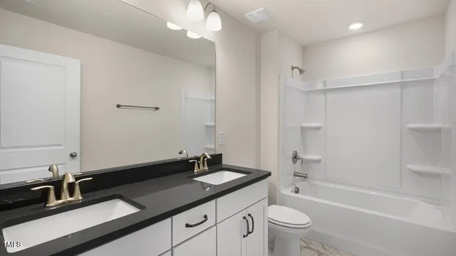 a bathroom with a double vanity sink toilet and shower