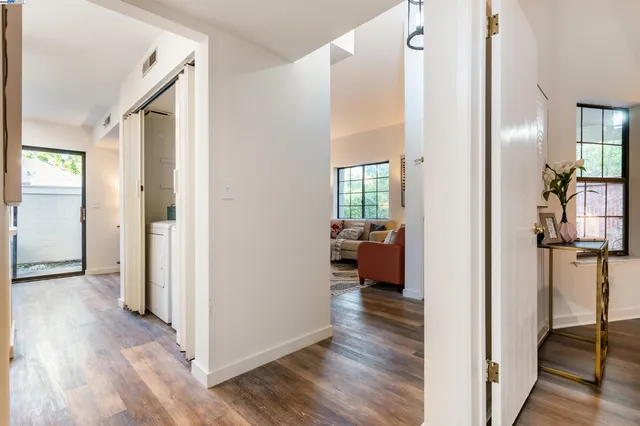 a view of a hallway with wooden floor and a living room