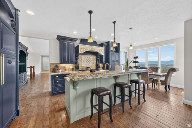 767 Draper View Road Draper, UT 84020 - Photo 10 of 71 Open-concept kitchen featuring dark wood cabinetry, a light-toned island with decorative corbels, and stone countertops