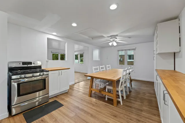 a open kitchen with stainless steel appliances granite countertop a stove a table and chairs with wooden floor