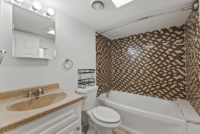 a bathroom with a bathtub sink vanity mirror and toilet