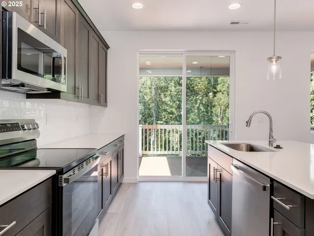 a kitchen with a sink a counter top space stainless steel appliances and cabinets