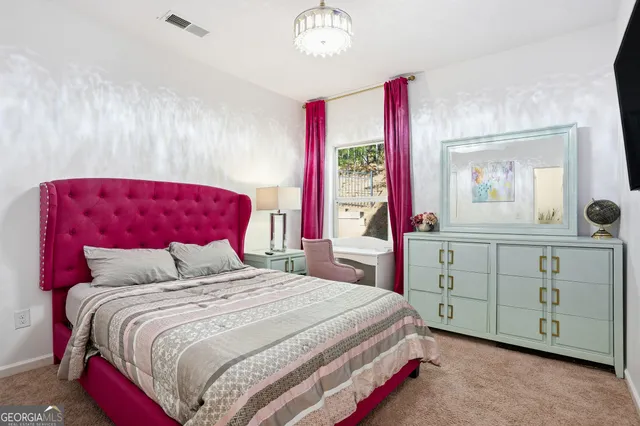 a bedroom with a bed a chandelier and mirror on dresser