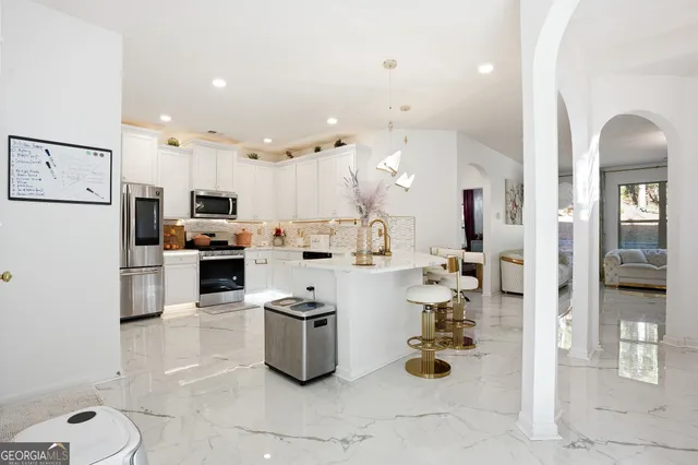 a kitchen with granite countertop a refrigerator a stove and white cabinets with wooden floor