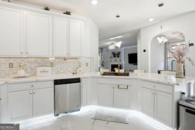 a kitchen with granite countertop a sink white cabinets and stainless steel appliances