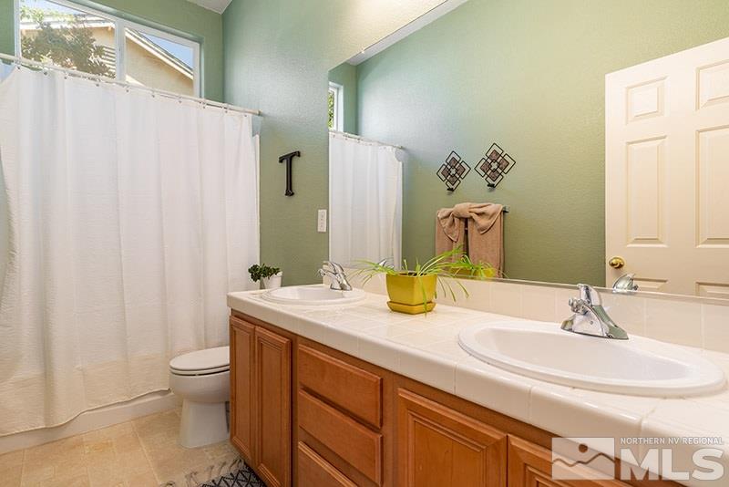1445 Hagar Road Reno, NV 89506 - Photo 15 of 23 a bathroom with a granite countertop sink a toilet and a mirror