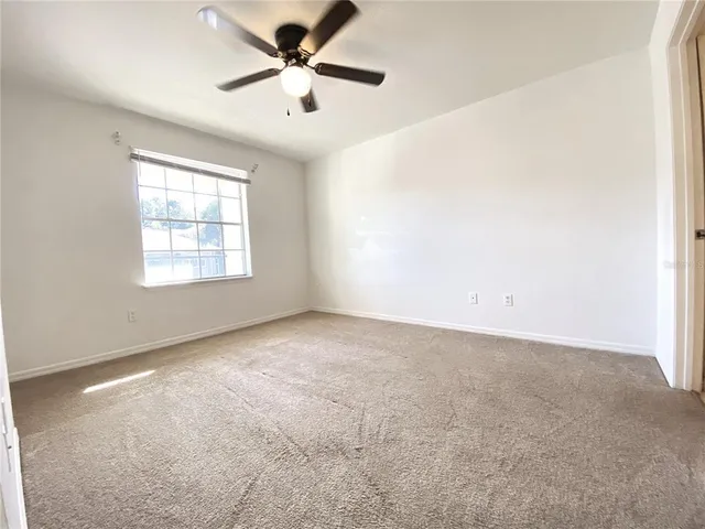 an empty room with windows and ceiling fan