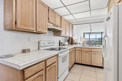 a kitchen with stainless steel appliances granite countertop a sink dishwasher and white cabinets with wooden floor