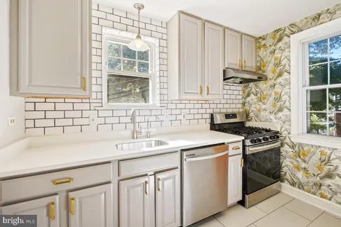 a kitchen with granite countertop a sink stove and cabinets