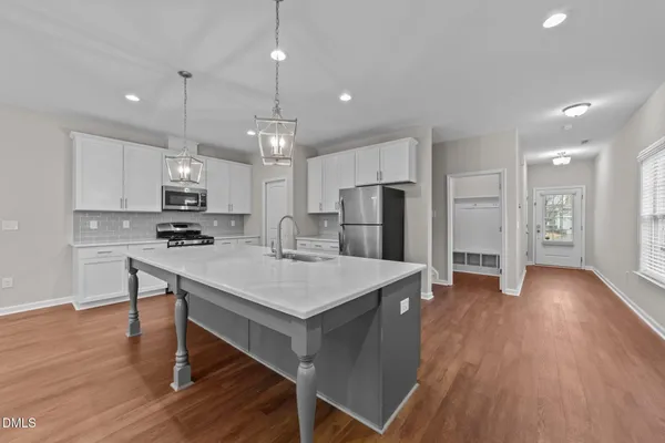 a kitchen with stainless steel appliances a table chairs refrigerator and wooden floor