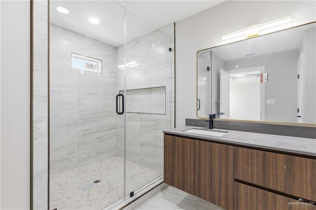 2206 Corales Street Mission, TX 78573 - Photo 10 of 19 a bathroom with a granite countertop sink a mirror and shower