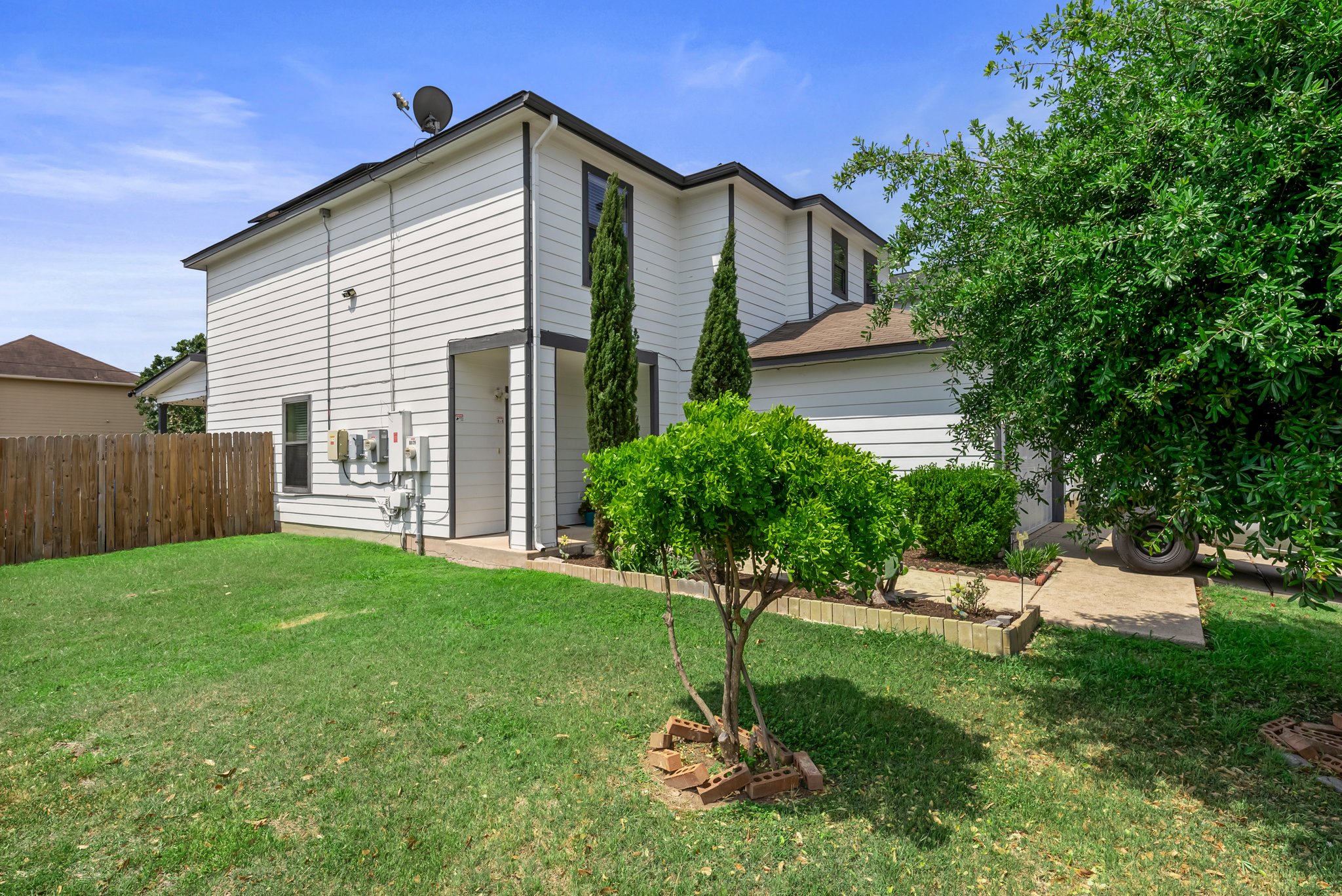 6829 Walkup Lane Austin, TX 78747 - Photo 2 of 18 A classic white siding exterior offers a crisp facade, complemented by lush greenery and a manicured lawn.