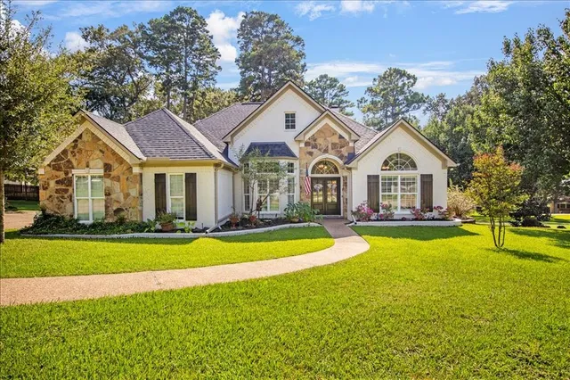 a view of a white house with a big yard and large trees