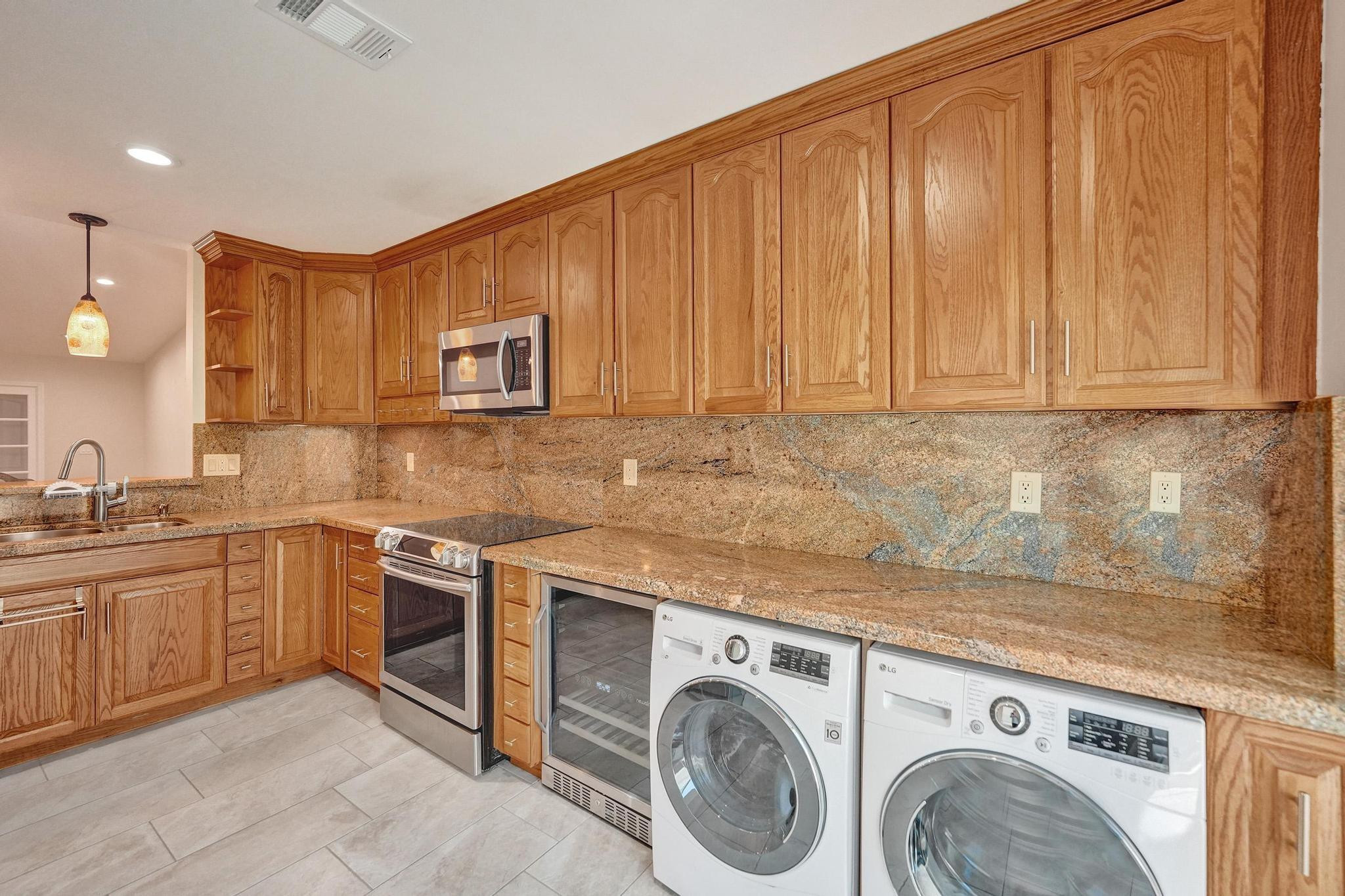 10896 Waterberry Court Boca Raton, FL 33498 - Photo 11 of 34 a kitchen with stainless steel appliances granite countertop a sink a stove and dishwasher with wooden cabinets