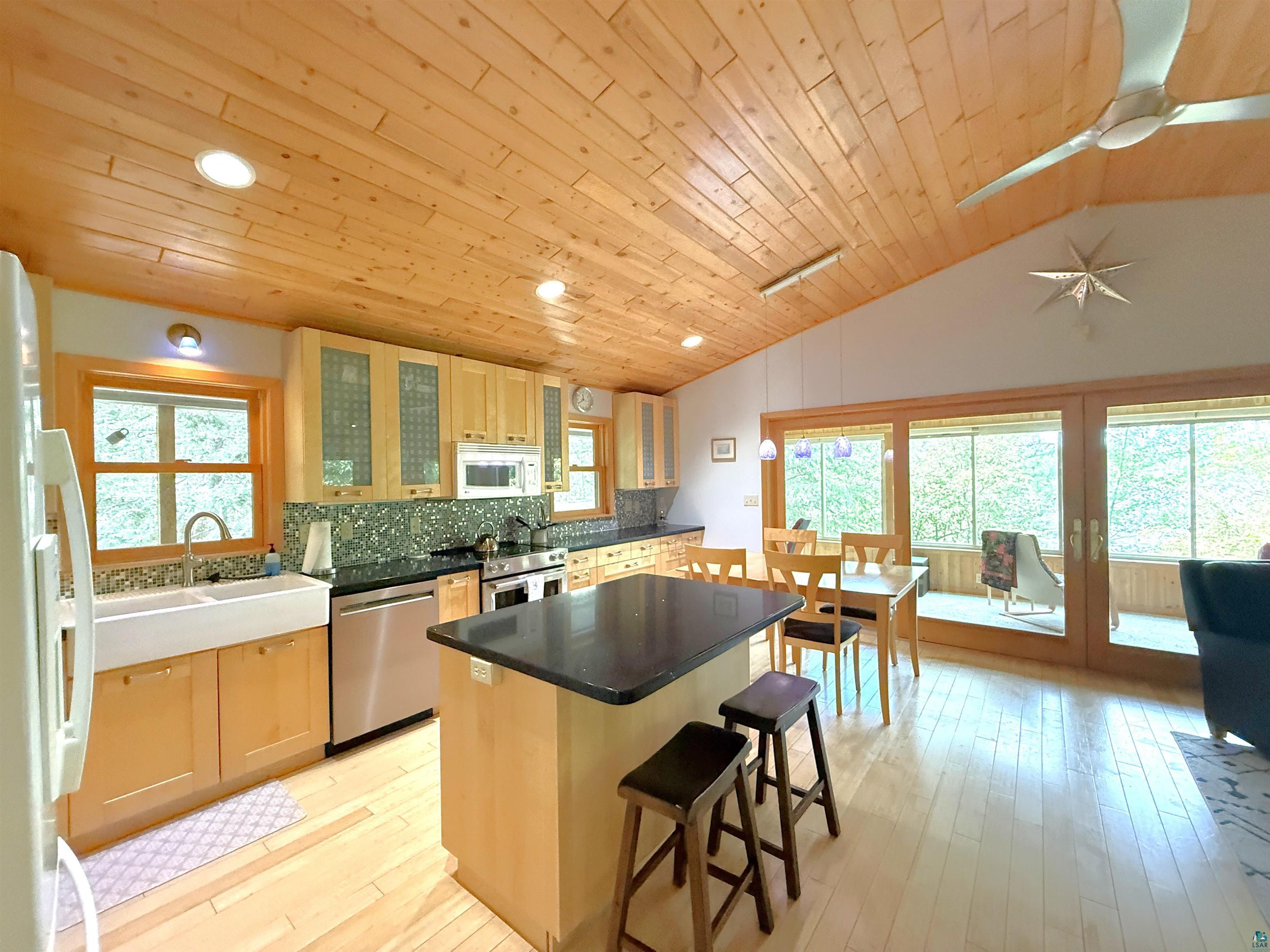 1787 North Bay Road Ely, MN 55731 - Photo 9 of 40 Kitchen featuring vaulted wood-paneled ceilings, light wood-finish flooring, and a central island with a dark countertop