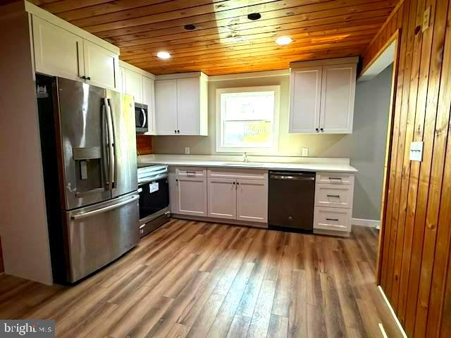 7699 Hedgesville Road Hedgesville, WV 25427 - Photo 14 of 47 a kitchen with stainless steel appliances granite countertop a refrigerator a sink dishwasher a stove and white countertops with wooden floor