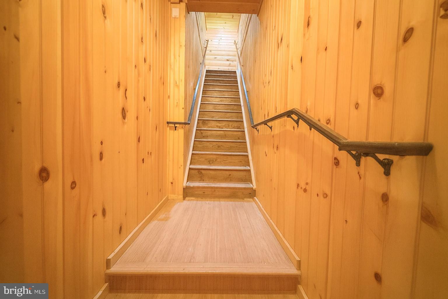 7699 Hedgesville Road Hedgesville, WV 25427 - Photo 32 of 47 a view of a hallway with wooden floor and black stairs