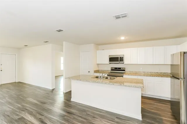 a kitchen with a sink and a stove top oven with wooden floor