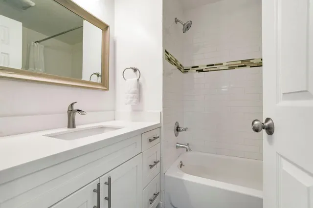 a bathroom with a tub sink and mirror