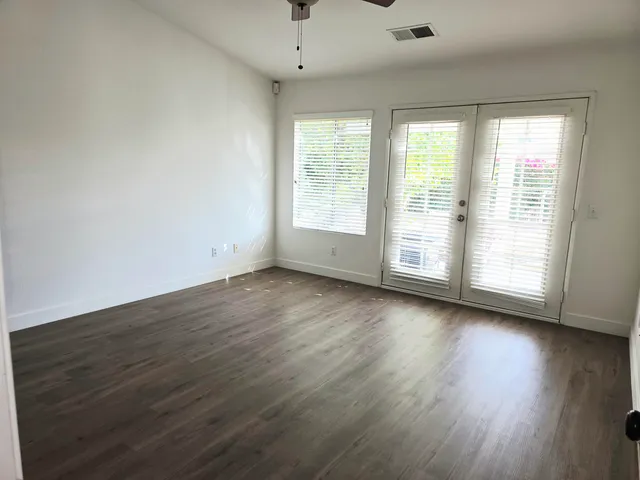 an empty room with wooden floor and windows