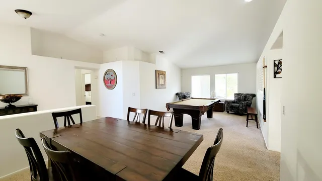 a view of a dining room and livingroom with furniture a rug a fireplace and a chandelier