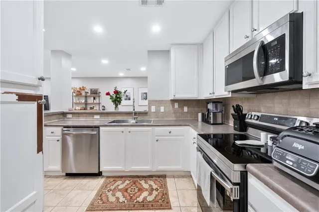 a kitchen with stainless steel appliances granite countertop a stove top oven a sink dishwasher and a microwave oven with the cabinets