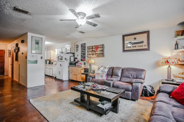 a living room with furniture kitchen view and a chandelier
