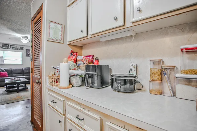 a kitchen with kitchen island a sink wooden floor and white cabinets