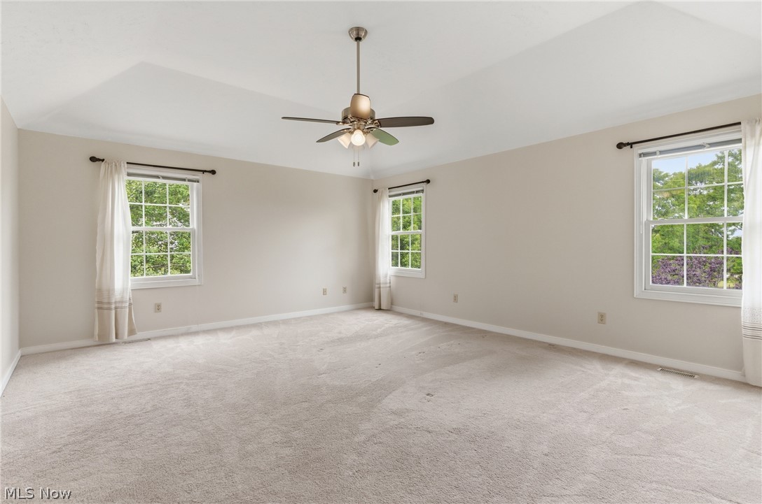 11678 Dunham Road Northfield, OH 44067 - Photo 20 of 38 Carpeted room featuring a tray ceiling, ceiling fan with integrated lighting, and multiple double-hung windows