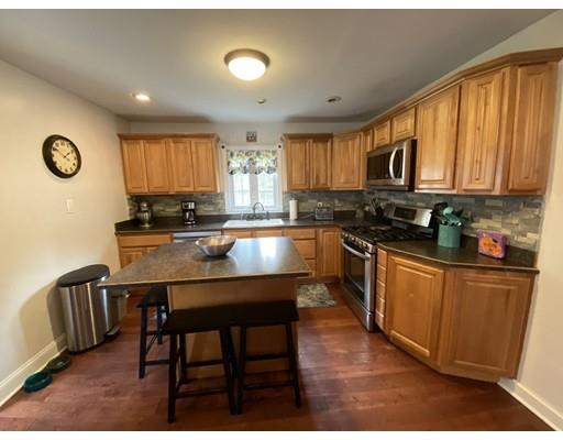 103 Chicago Street Fall River, MA 02721 - Photo 8 of 39 a kitchen with stainless steel appliances granite countertop a stove top oven a sink a dining table and chairs with wooden floor