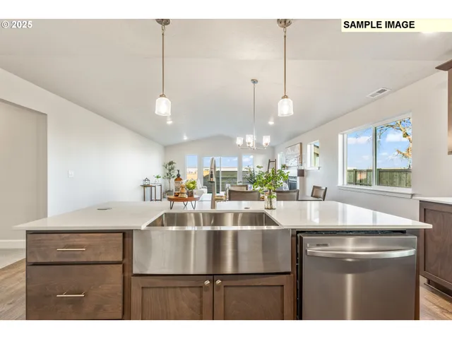 a kitchen with a sink a counter top space and living room view